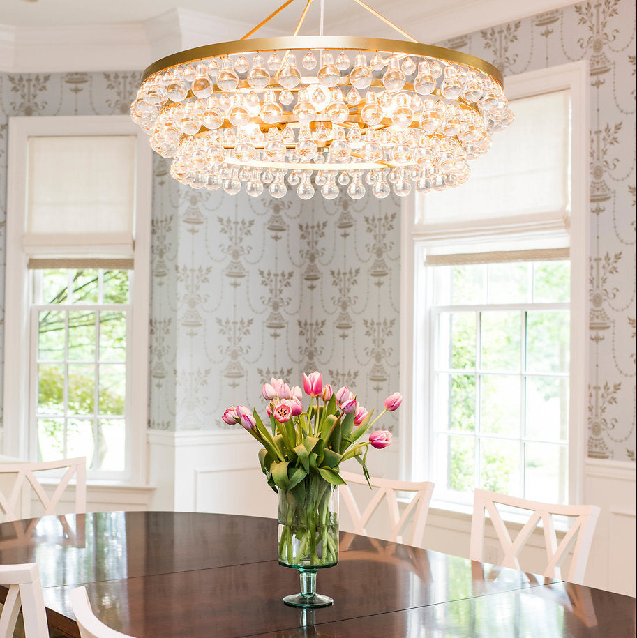 Dining room with a wooden table, white chairs, and a chandelier.