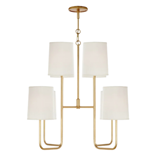 A gold-finished chandelier with white linen shades, featuring a geometric design with three main lighting branches and additional smaller branches.